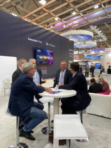 A group of ANGACOM 2023 attendees meet at the DZS booth in Germany.